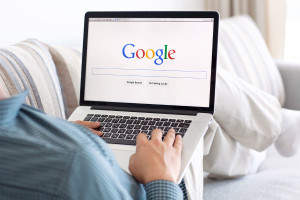 sitting on the couch looking at google search on computer